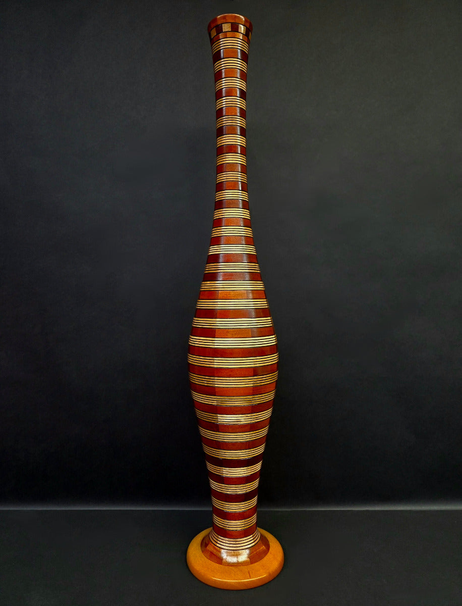 Tall, striped wooden vase against a dark background
