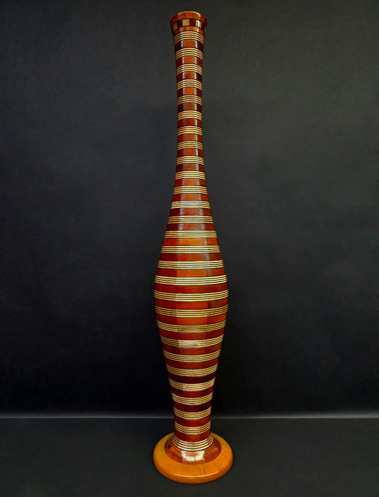 Tall, striped wooden vase against a dark background