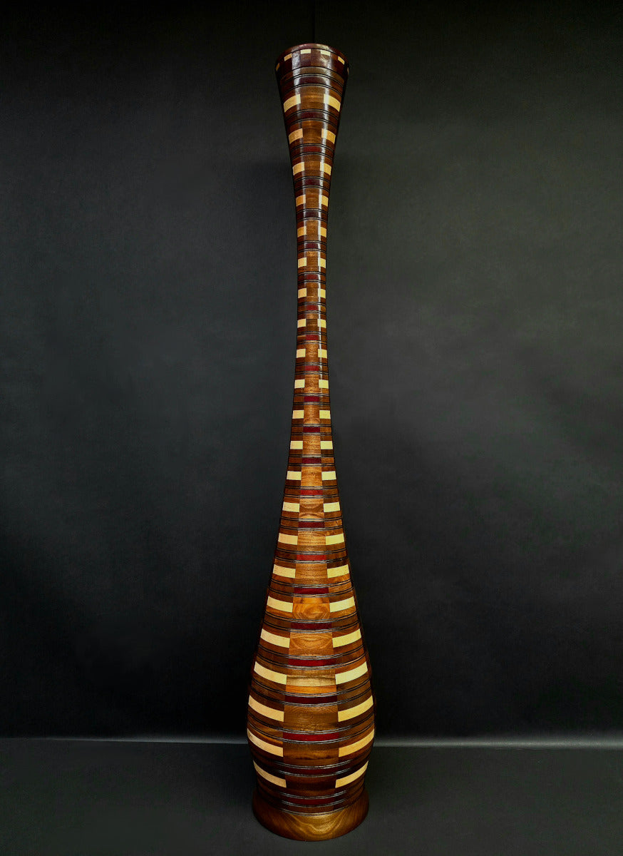 Tall, multicolored wooden vase against a dark background